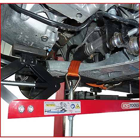 Ein roter Unterstellbock stützt ein Auto ab. Ein orangefarbenes Spanngurt ist befestigt. Auf dem Bock steht "KS TOOLS".